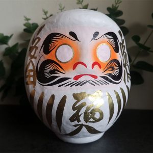 White Japanese daruma doll that is 15cm tall with gold details